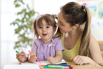 Kindergarten teacher and kid girl drawing lessons at school