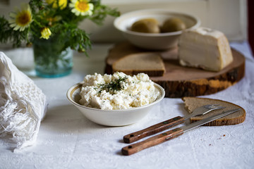 fresh Italian ricotta with rye homemade bread and lard on the table, rustic still life with spring flowers, Salento, Apulia