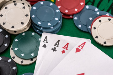 Poker chips and four ace on green table