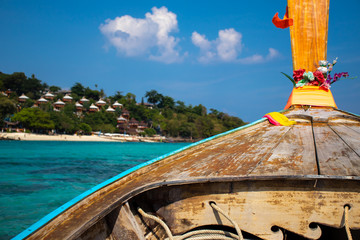 Photo taken from a Thai long-tail boat floating on an emerald sea with a bungalow resort at Koh Phi Phi island in the background.