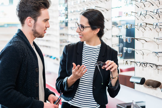 Woman and man buying glasses in optician store