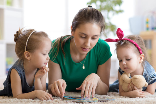 Cute mom and her two daughters children reading together