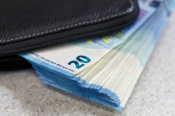 Large stack of money worth 20 euros are stick out of the purse