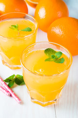 Close-up of a glass of orange juice with oranges fruits on wooden and stone background. Vitamins and minerals. Healthy drink and beverage concept.