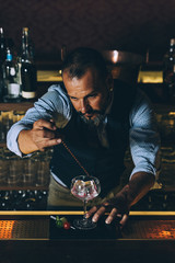 Barman is making cocktail at night club.