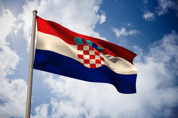 Croatia national flag against bright blue sky with clouds