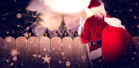 Santa steps up a ladder against fence under blue sky