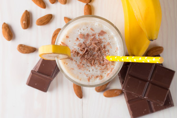 Fresh Made Chocolate Banana Smoothie on a wooden table. Selective focus. Milkshake with almonds. Protein diet. Healthy food and drink concept.