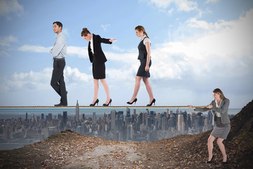 Young businesswoman pulling a tightrope for business people against large city on the horizon