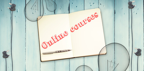 The word online courses against notepad and bulbs on wooden background