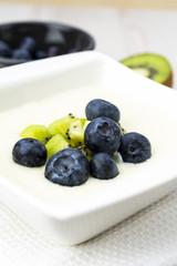 Semolina pudding with kiwi fruit and blueberries, sweet healthy and vegetarian meal concept.