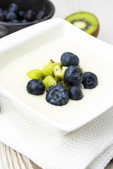 Semolina pudding with kiwi fruit and blueberries, sweet healthy and vegetarian meal concept.