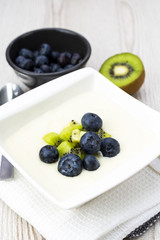 Semolina pudding with kiwi fruit and blueberries, sweet healthy and vegetarian meal concept.
