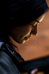 Indoor portrait of young beautiful model of mixed race dressed in gray coat standing at the staircase of brick building looking downstairs