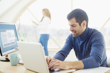 Young man working at the office. Handsome businessman wearing casual clothes while sitting at...