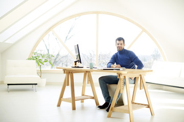 Businessman using laptop. Portrait of young financial assistant businessman wearing suit while sitting at office desk and working on financial report. 