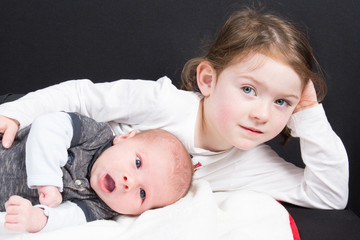First and second child together in family Little sister hugging her newborn baby brother