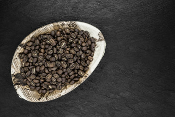 Bunch of Coffee Beans in Natural Banana Leaf Plate on Black Stone Background Surface