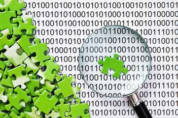 puzzles and magnifying glass on a binary code