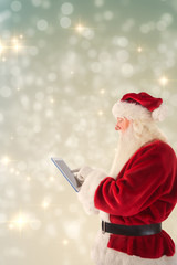 Santa uses a tablet PC against light design shimmering on silver