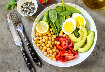 Healthy salad bowl with chickpeas, goose meat , tomatoes, avocado, lemon and spinach