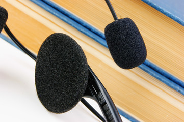 Headphones with a microphone and a stack of books isolated on white background