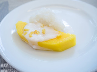 sweet mango with sticky rice with coconut milk on white plate