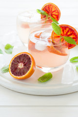 Blood orange cocktail with slices of orange on white wooden background