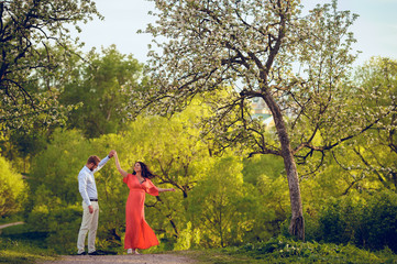 Romantic portrait of young smiling happy couple of lovely future parents during sunset on nature apple tree background in the city park. Pregnancy pregnant future mother photoshoot. Motherhood photo