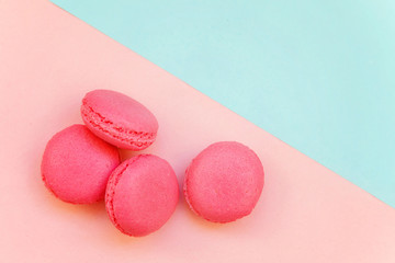 Top view of mini pink macaron or macaroon french desserts cake on soft sweet pink and blue pastel geometric paper flat lay background