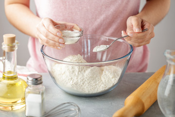 Women adds the baking powder into the glass bowl with flour. - 203117709