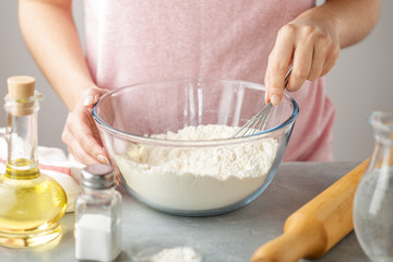 Woman mix flour with baking powder and salt in the glass bowl with whisk. - 203117750