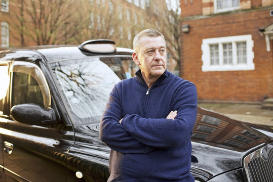 Portrait of taxi driver in front of his cab