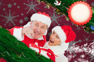 Festive mature couple holding gift against snowflake wallpaper pattern