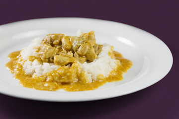 Simple dish from India. Chicken Korma. Chicken on a mildly spiced coconut creamy sauce served with rice on white plate.