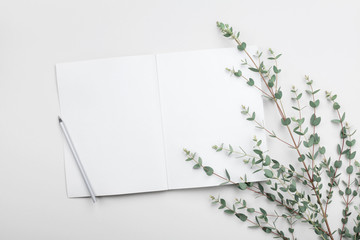 Open empty notebook and eucalyptus leaf on gray table from above. Minimalistic working desk. Flat...
