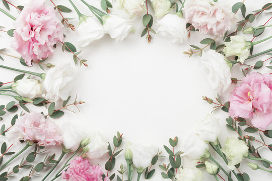 Fototapeta Piękna kwiecista rama pastelowi kwiaty i eukaliptusowi liście na białym stołowym odgórnym widoku. Płaski układ.
