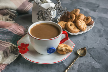 Morning coffee with milk in the original white Cup with a blue button on the background of the cookies