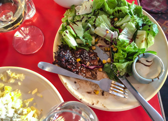 Glass of white wine. Salad from green leaves with chicken steak, cucumber, sesame seeds, corn with sauce