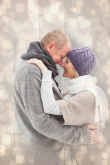 Happy mature couple in winter clothes embracing against light glowing dots design pattern