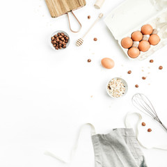 Food ingredients on white background. Cooking flat lay, top view concept. Eggs, apron, cutting board, hazelnut, cereals on white background. Mock up.