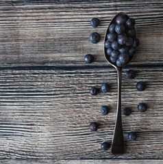 A spoonful of blueberries on a wooden table top with copy space