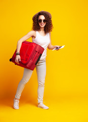 Woman traveler with suitcase on color background.