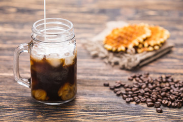 Ice coffee and coffee beans on the background.