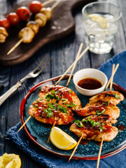 Chicken kebab on skewers with cherry, mushrooms and barbecue sauce on a blue background