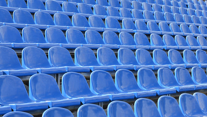 Rows of blue seats in the stands. Athletic facilities.