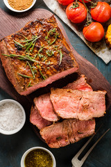 Sliced Roast beef on cutting board with grilled vegetables. Top view