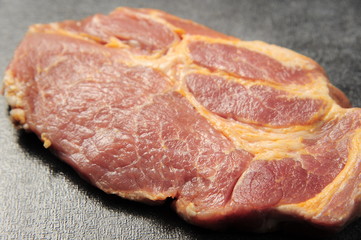 Raw pork meat on a dark gray