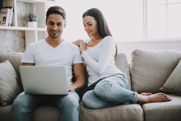 Young couple spend leisure time with laptop at home.