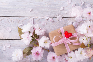 Kleines Geschenk mit Herz und Blüten auf Holz  -  Grußkarte, Hintergrund 